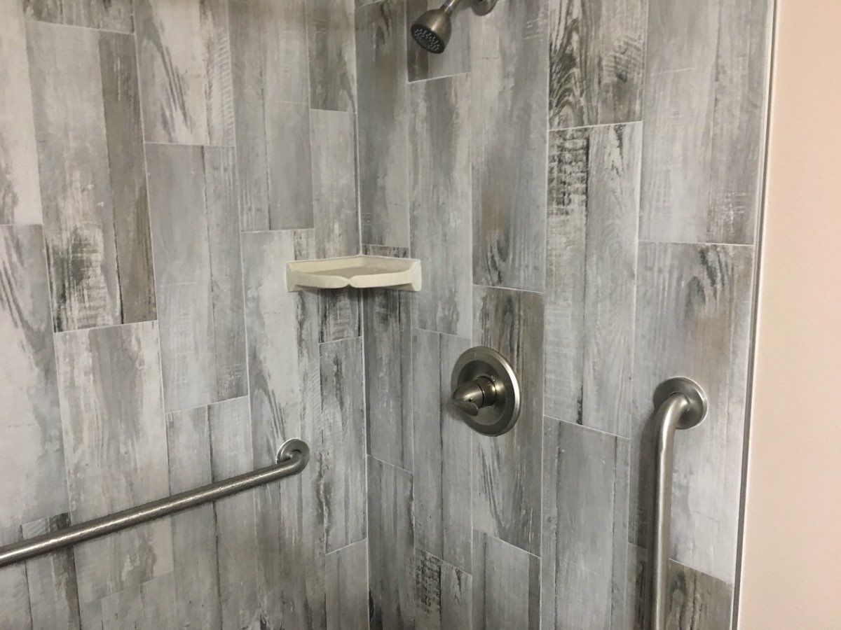 Finished tiled walk-in shower with grab bars, installed by All Service Plumbing