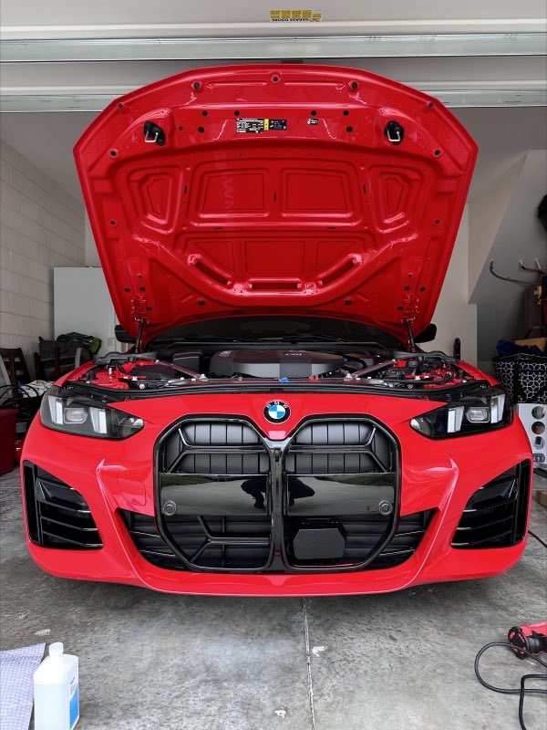 Engine work on a red BMW M4, hood up