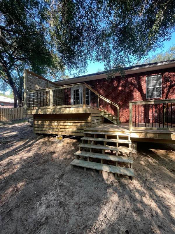 Multi-level wood deck with stairs and railings built onto a brick home