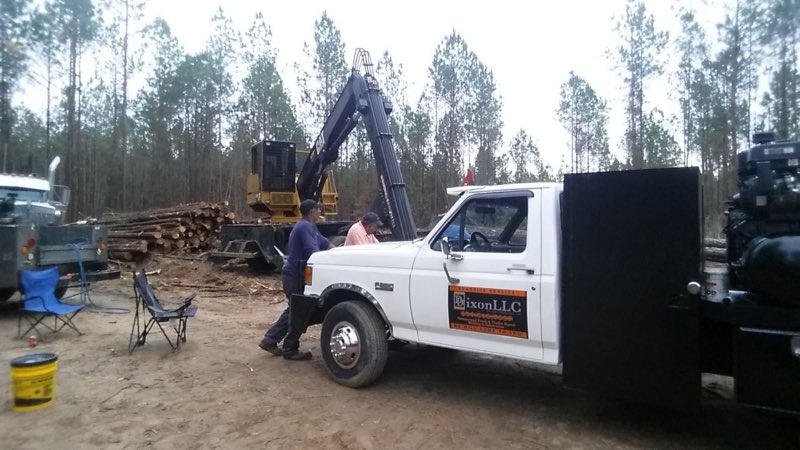 Working on a truck out front with a log loader on site