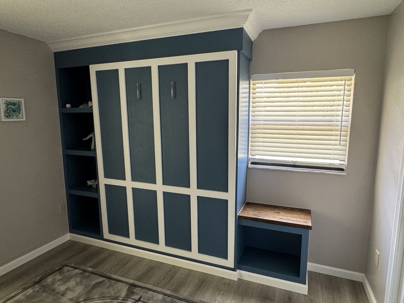 Custom navy-and-white Murphy bed built-in with matching shelving and a wood-topped bench