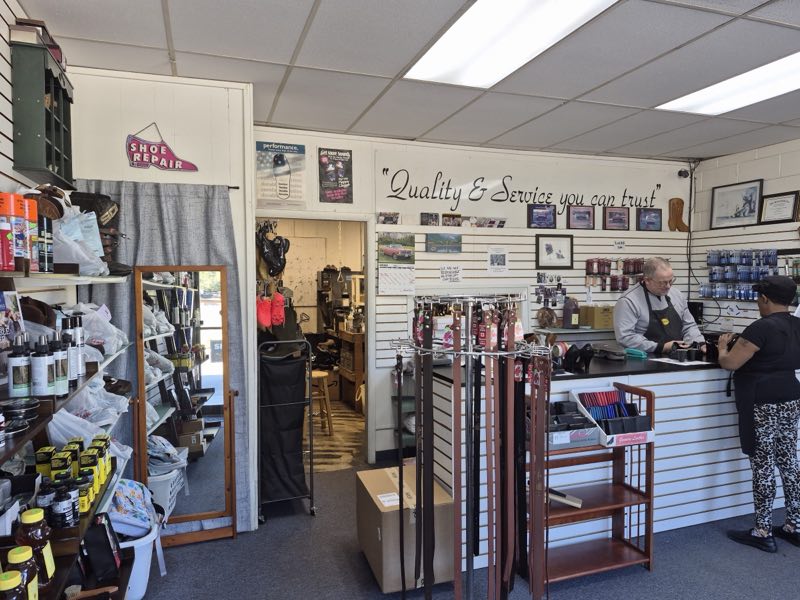 Interior of Edgewood Drive Shoe Repair: front counter, shelves of shoe-care products and the painted 'Quality & Service you can trust' wall sign