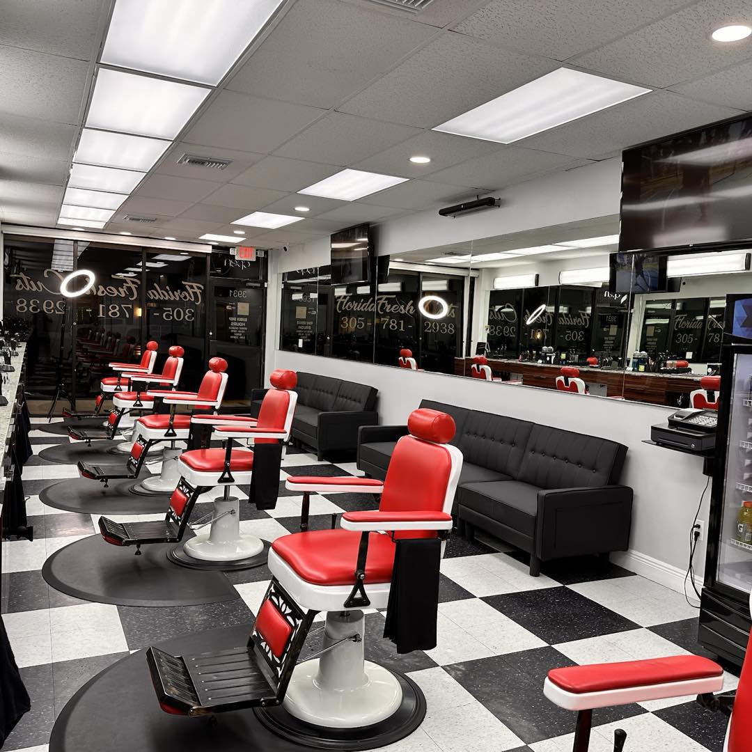 Inside Florida Fresh Cuts: a row of red barber chairs on a black-and-white checkerboard floor with big mirrors