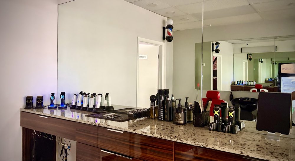 A tidy barber station at Florida Fresh Cuts: a lineup of clippers, styling products and combs on a granite counter