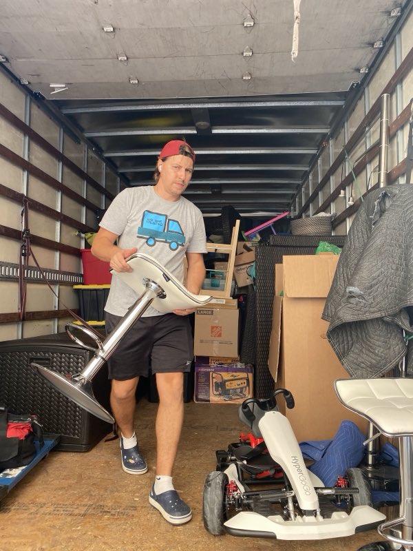 Florida Smart Moving crew member in a branded shirt carrying furniture inside the truck