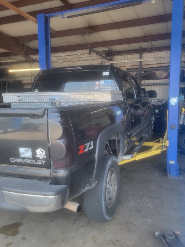 Black Chevrolet pickup raised on the shop lift