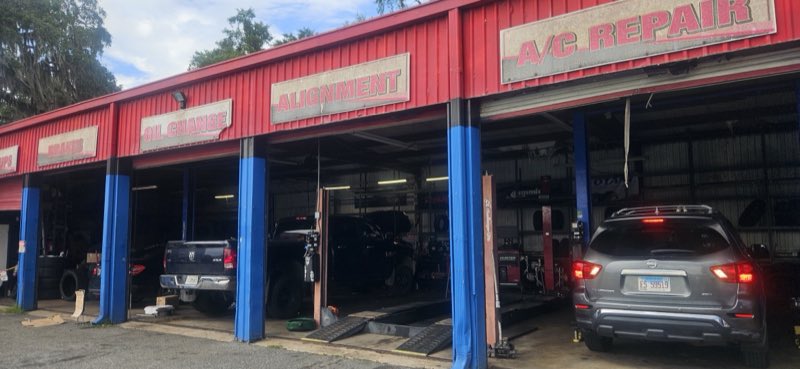 Open service bays labeled Oil Change, Alignment and A/C Repair with trucks being serviced