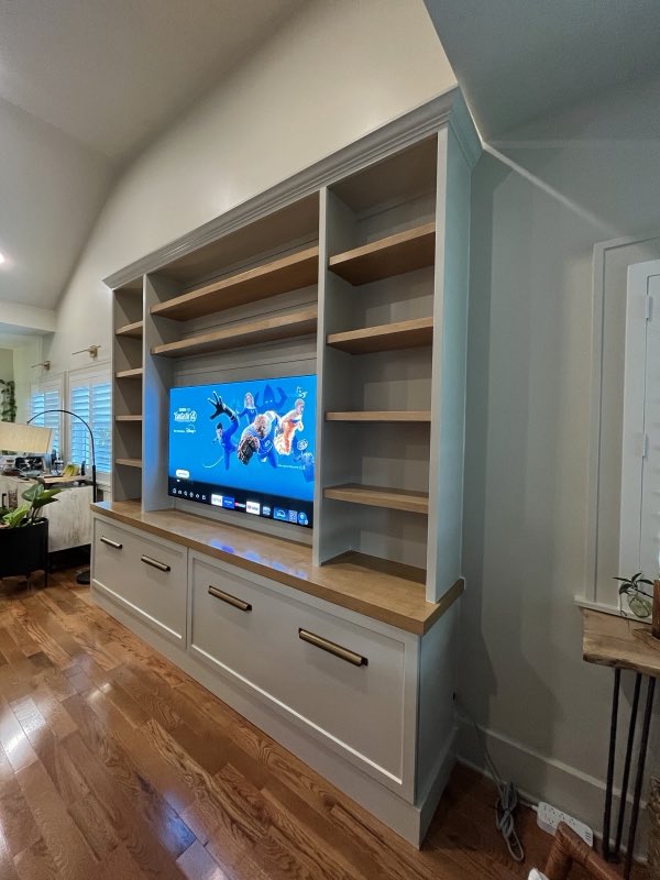Greige media room entertainment center with open wood shelves, drawers and a wood counter