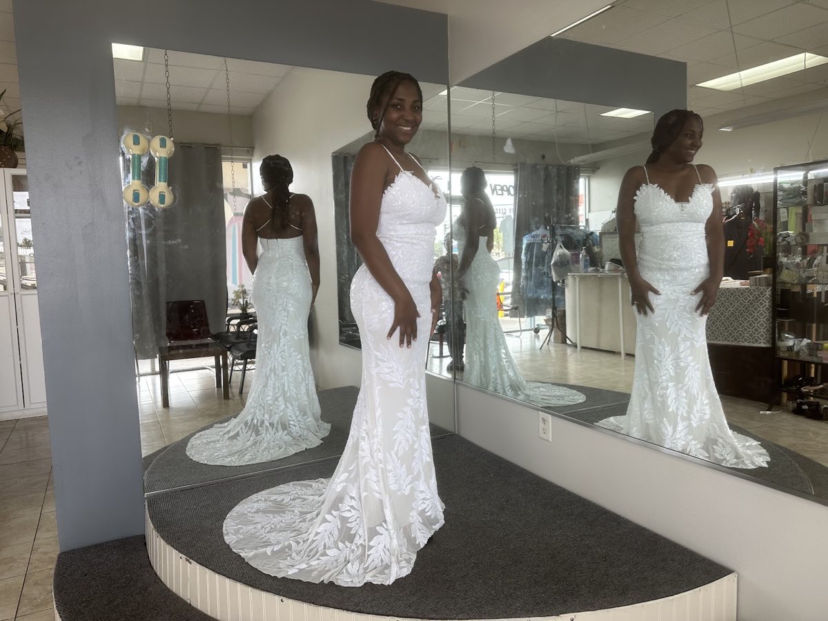Bride in a fitted white lace mermaid wedding gown on the fitting platform at Hue's Tailor & Alterations