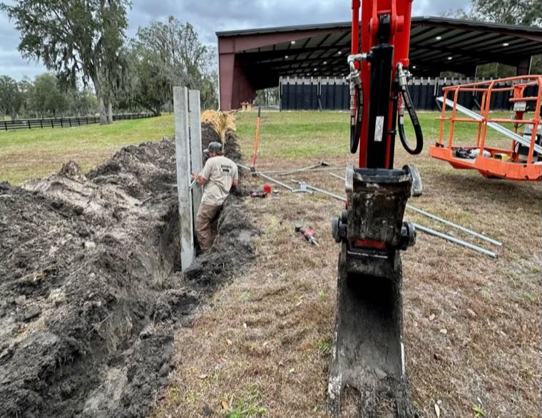 Crew replacing a utility pole with an excavator on a rural property