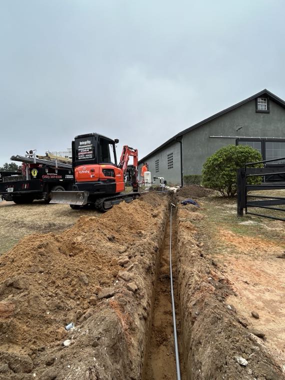Underground service trench with conduit running toward a barn