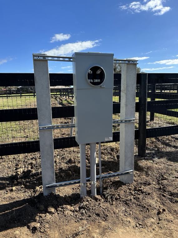 Finished meter pedestal installation mounted at a ranch fence line