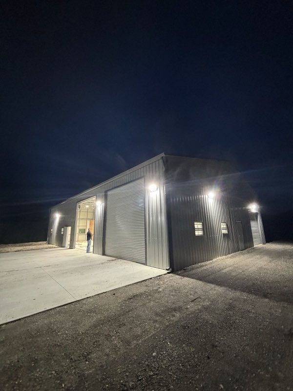 Night exterior of a metal barn lit by newly installed lights