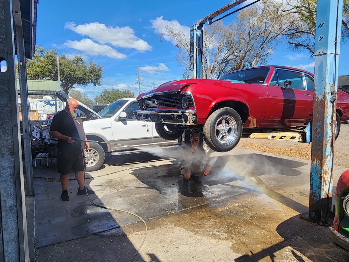 A red classic Chevrolet up on the lift being detailed at John's Auto & Classics