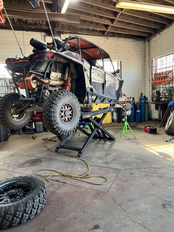Polaris RZR side-by-side raised on a scissor lift inside the shop