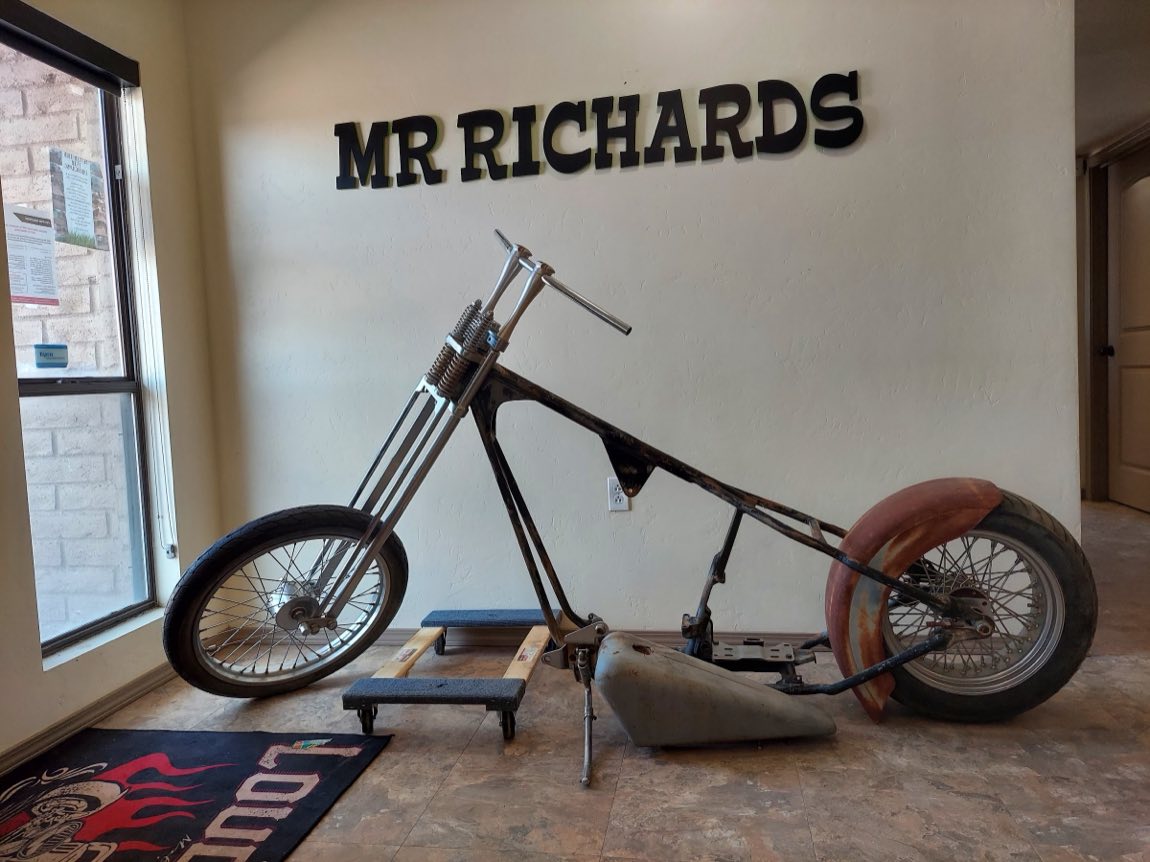 Custom chopper build in progress beneath the MR RICHARDS lettering inside the shop