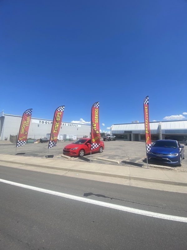 Shop exterior with service feather flags and customer cars in the lot
