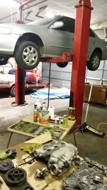Vehicle on the lift with a transmission rebuild laid out on the bench