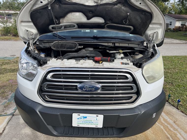 Ford Transit van with hood open being serviced in a driveway