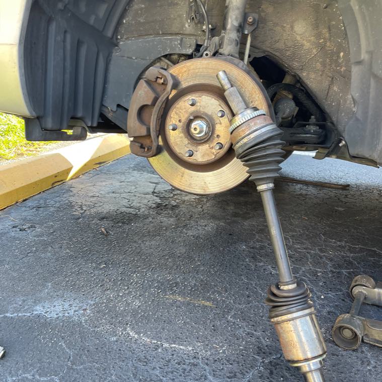 Brake rotor and CV axle removed and mid-repair on a raised car