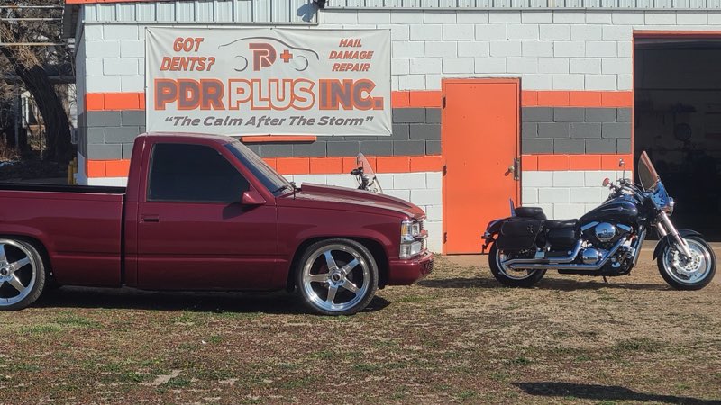 PDR Plus Inc storefront banner with a lowered maroon Chevrolet truck parked outside