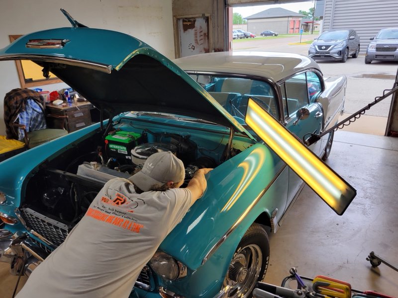 Technician using the PDR light board on the fender of a classic teal Chevrolet