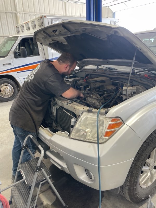 Technician working under the hood of a customer SUV