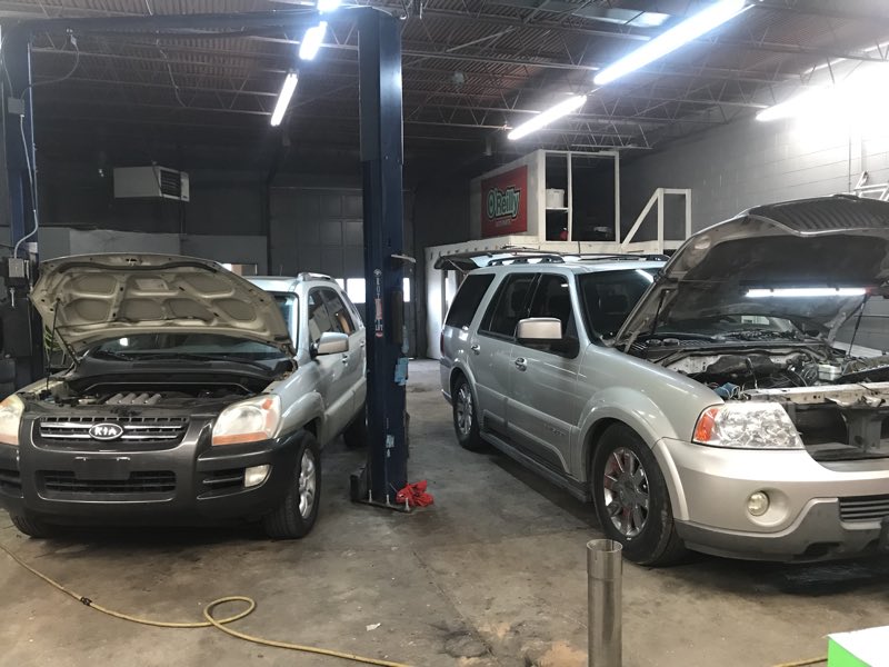 Two SUVs up on the lifts in the service bay