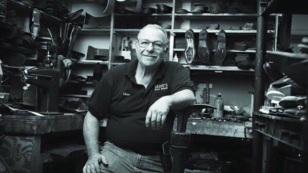 Black-and-white portrait of the craftsman seated in the Silvio's workshop.
