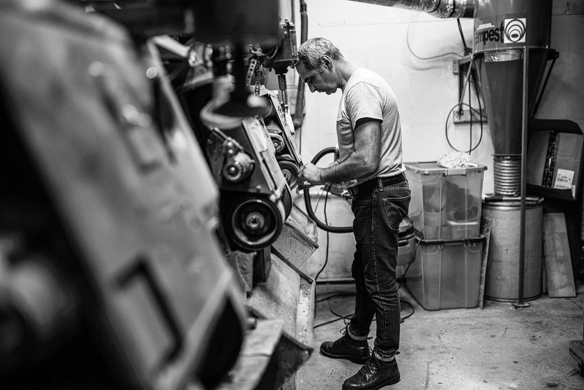 A craftsman at Silvio's works a shoe against the finishing machine in the workshop.