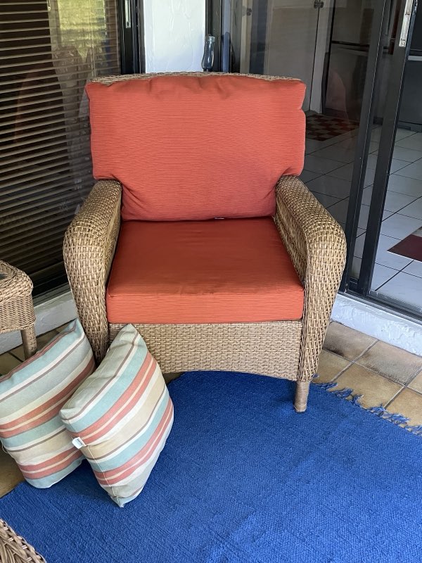 Wicker armchair reupholstered with orange cushions and striped pillows